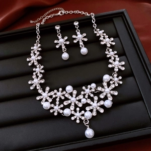 Close-up of pearl flower necklace and earrings set displayed on red silk fabric