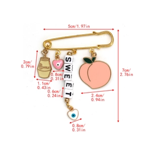 Macro view of gold safety pin brooch with Sweet charms and Devil's Eye pendant details