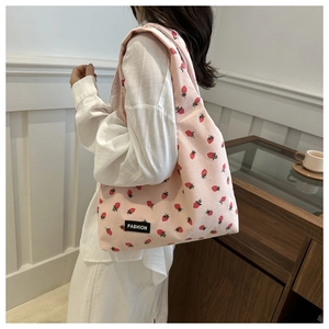 Detail of pink corduroy tote bag with strawberry prints and a black fashion label