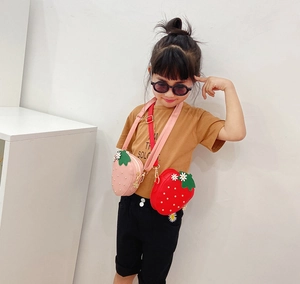 Detail shot of cute strawberry-shaped kids crossbody bags in pink and red colors