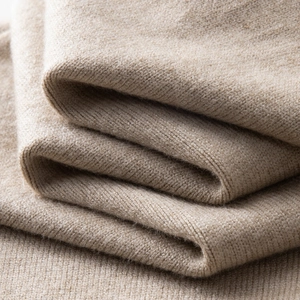 Makro-Detail der hochwertigen Kaschmir-Stricktextur in Haferflockenbeige und Nahtdetails