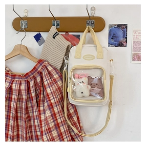 Cream canvas Ita bag detail showing transparent PVC window with white plush toy inside