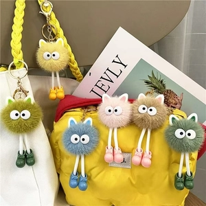 Detail of colorful plush monster keychains hanging on bags with gold metal hooks