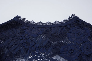 Close-up van marineblauw bloemenkant en opengewerkte borduurdetails op een slanke top