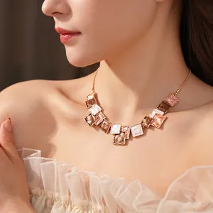 Elegant gold necklace with square marble enamel pendants worn by a model in a close-up shot