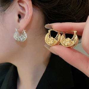 Macro detail of hollowed crescent earrings with intricate 3D floral metalwork