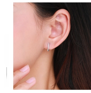 Macro shot of silver S925 sterling silver hoop earrings with pavé set crystals on model