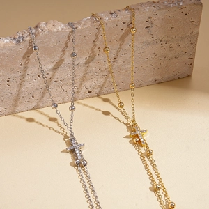 Gold and silver layered cross pendant necklaces with cubic zirconia on a stone display