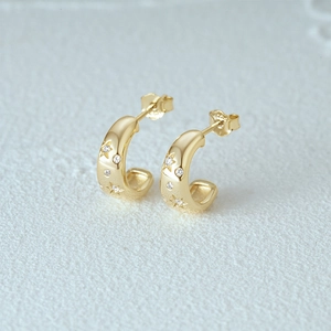 Detail of S925 silver gold hoop earrings with star engraving and white zircon stones
