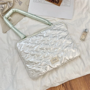 Detailed shot of quilted laptop sleeve with silver bow patterns and green handles