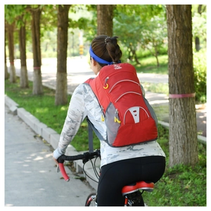 Rear view of model wearing a lightweight red cycling backpack with reflective safety patches