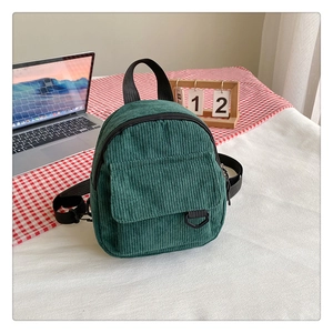 Detailed texture of dark green corduroy backpack with zipper on a plaid background