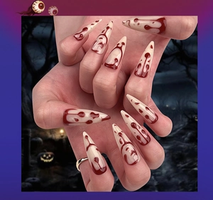 Macro detail of long stiletto Halloween fake nails featuring realistic dark red blood drips