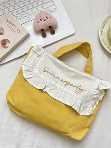 Yellow canvas handbag with ruffled edge and Summerparty embroidery on a desk