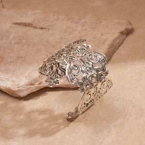Detailed view of silver filigree hollow floral pattern on a wide open cuff bracelet