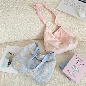 Détail de sacs cabas en tissu brodé avec motifs de papillons et texture douce et chic