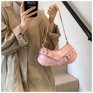 Close-up of pink leather underarm bag with silver grommets and buckle details