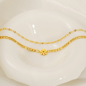 Double-layer gold Cuban anklet with daisy flower pendant on white ceramic display