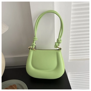 Detail of lime green saddle bag with quilted texture, knotted strap and gold zipper