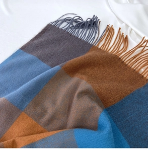 Detailed view of blue and brown plaid scarf with soft cashmere texture and fringe tassels