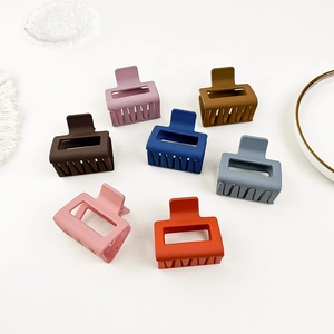 Top view of seven colorful matte mini hair claws arranged neatly on a white surface
