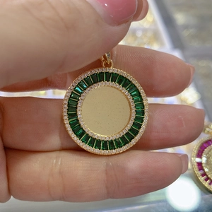 Macro view of gold pendant with green rectangular crystals and white stones