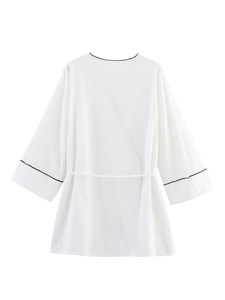 Détail du haut style kimono blanc avec bordures noires contrastées et tissu léger texturé