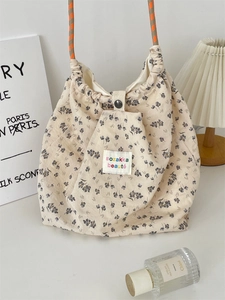 Detail of floral canvas tote bag with drawstring closure and braided orange handles