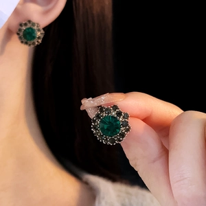 Detail shot of vintage flower stud earring with green gemstone and sparkling accents