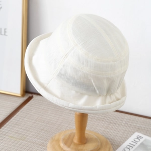 Detailed macro view of the cream-colored bucket hat showing textured fabric and rolled edge