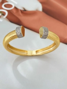 Detail of gold open bangle with ribbed texture and shimmering micro-set diamond ends