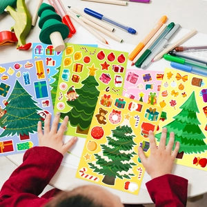 Kids hands playing with DIY Christmas tree face change stickers for holiday craft fun