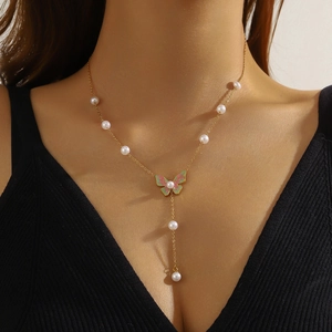 Elegant gold butterfly necklace with pink enamel and pearl tassels worn by a model