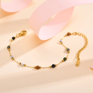Close-up of golden stainless steel chain with colorful natural stone beads on a yellow base