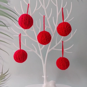 Five 5cm red yarn ball Christmas ornaments hanging on a white decorative display stand