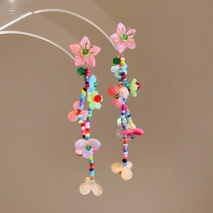 Close-up of long tassel floral earrings with colorful beads and pink translucent petals