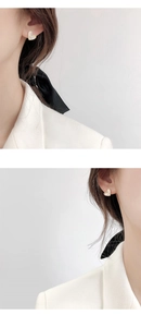 Close-up of heart-shaped gold earrings with white pearl inlay on a female model