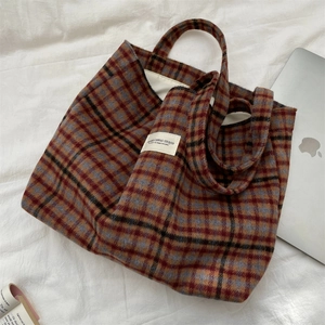 Detail of vintage plaid wool tote bag with textured fabric and wide strap on white cloth