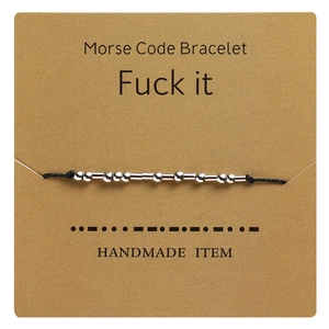 Detail view of handmade Morse code bracelet on kraft card showing dots and dashes