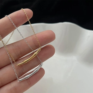 Colliers minimalistes avec pendentifs bambou en or et argent sur une assiette en céramique