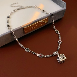 Detail of vintage silver flower necklace with colorful gems and gothic cube pendant