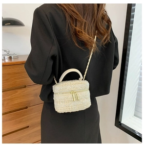Chique crème tweed emmertas met gouden ketting gedragen over een zwarte blazer