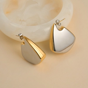 Macro detail of high-polish mixed gold and silver fan-shaped geometric stud earrings