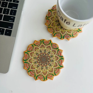 Close-up of vibrant orange and green mandala pattern ceramic coasters on a white table