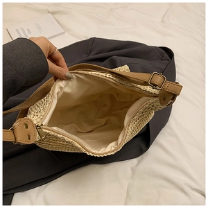 Detail shot of woven straw bag interior with zipper closure and brown leather strap