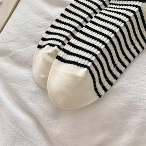 Detailed close-up of soft black and white striped wool socks with a white toe cap design