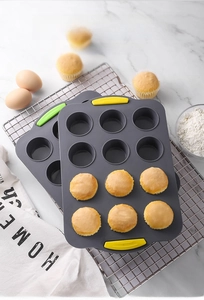 Detail of 12-cup silicone muffin pans with anti-slip handles on marble background