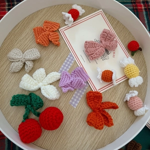 Detailed assortment of handmade crochet bows and cherries in various colors on a wooden tray