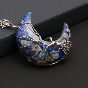 Macro shot of silver wire-wrapped tree of life design on a blue moon crescent pendant