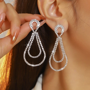 Elegant long silver drop earrings with glittering rhinestones worn by a model